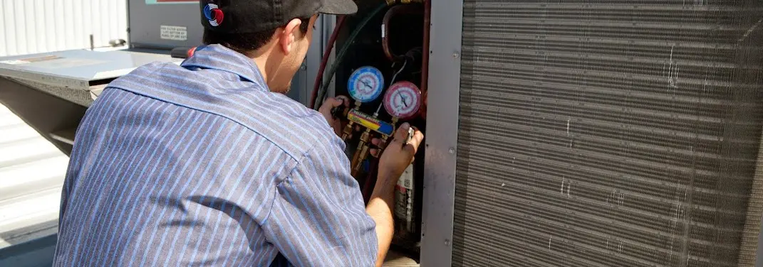 HVAC technician servicing a condenser unit in Marlboro
