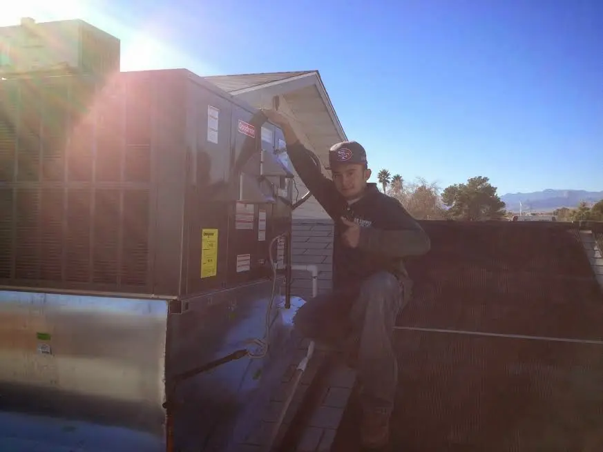 HVAC technician performing Air Duct Cleaning on a rooftop unit in Marlboro